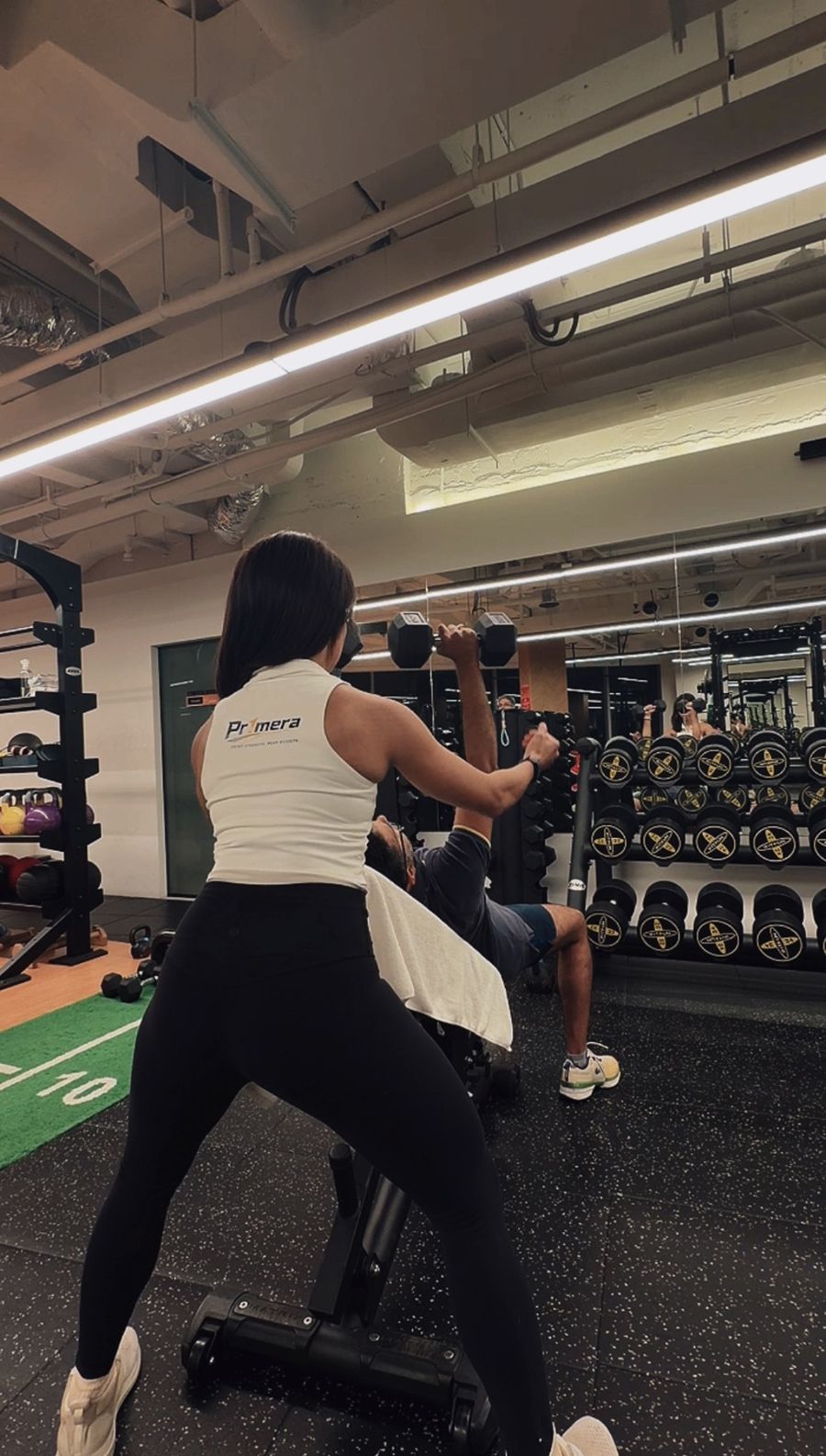 Patricia spotting a client through a set of incline dumbbell presses.